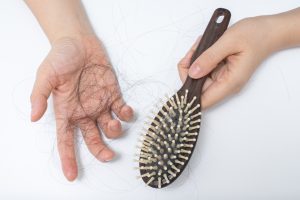 Brosse à cheveux et main avec des cheveux