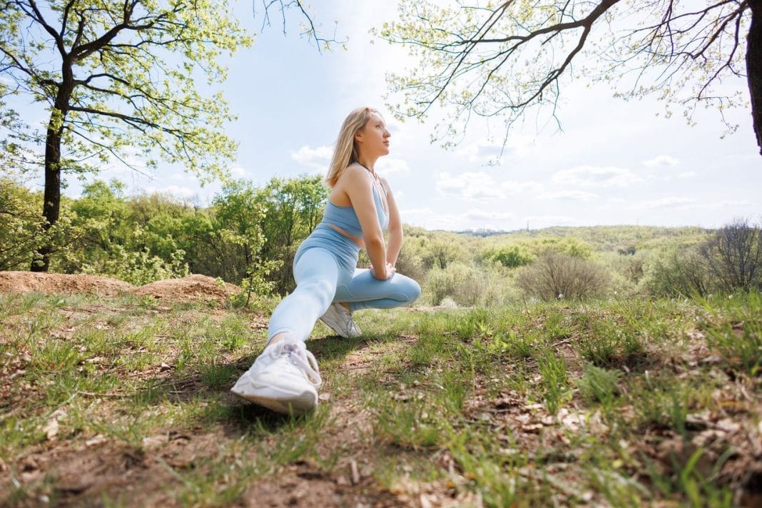 Beautiful blonde Caucasian woman in blue tight tracksuit. Blonde girl at an outdoor training session